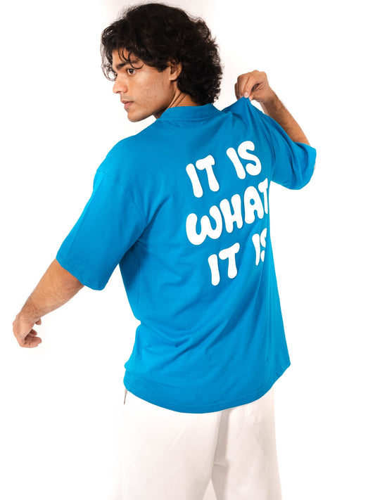 Model showcasing back of a blue Vako 'It is what it is' T-Shirt with bold white lettering