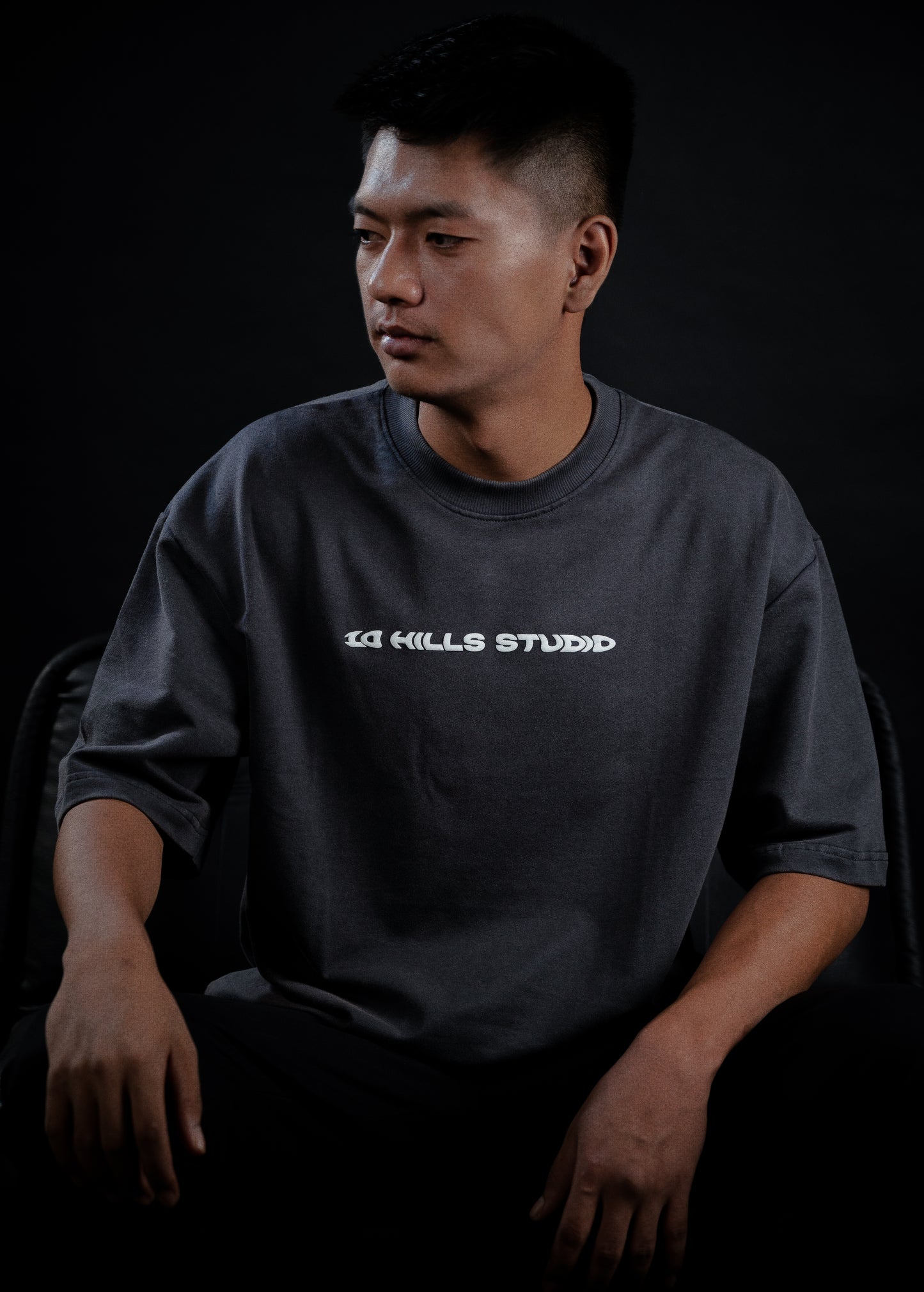 Front view of Model sitting while wearing the 10 Hills Studio Vintage Black Logo Tee