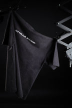 Front view of 10 Hills Studio Vintage Black Logo Tee hanging with the help of two ceiling supports in a dark contrast style photography