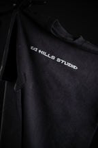 Front view of 10 Hills Studio Vintage Black Logo Tee hanging in a dark contrast style photography