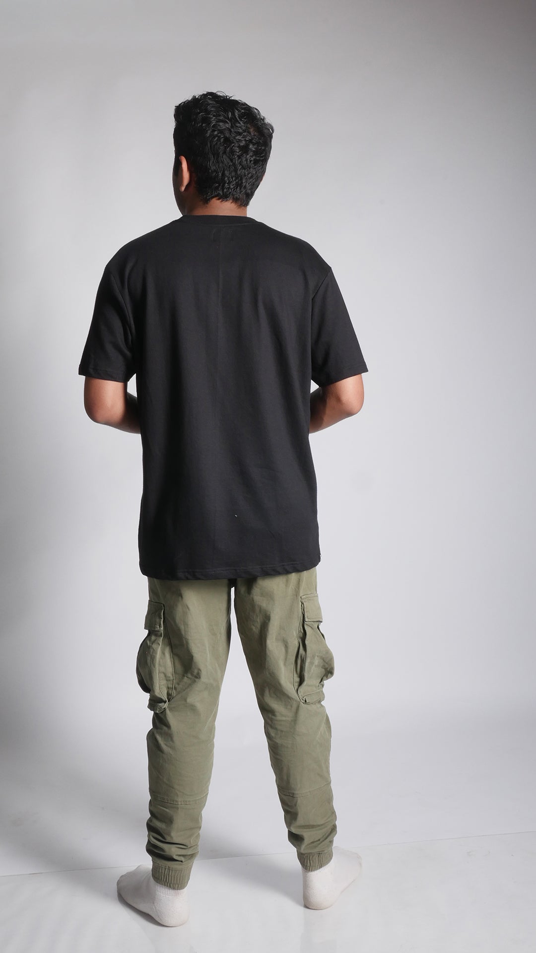 Back view of male model wearing 10 Hills Studio Unisex 'Lovers Paradise' Black Boxy T-Shirt